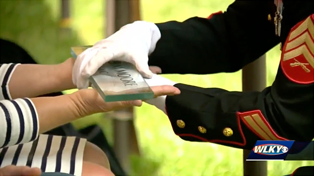 Soldier handing glass block to family member